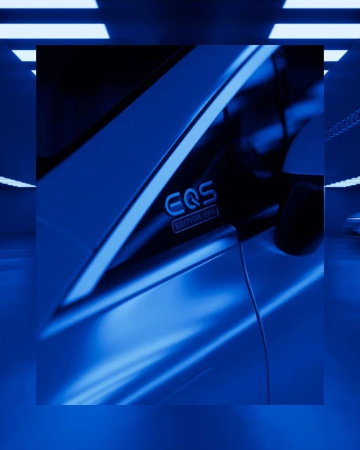 Close-up of a blue EQS Edition One car detail against a blurred tunnel background, showcasing automotive design in cool tones.