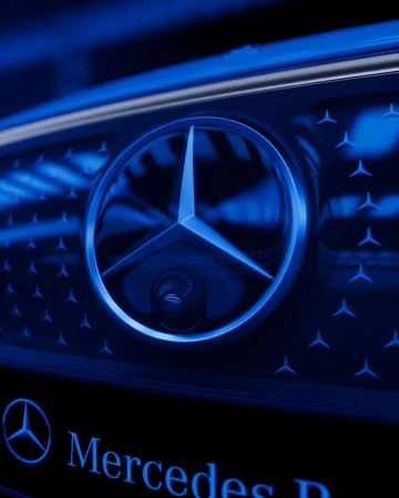 Close-up of a blue Mercedes-Benz emblem on a car grille with a repeating star pattern. Automobile branding with a luxury aesthetic.