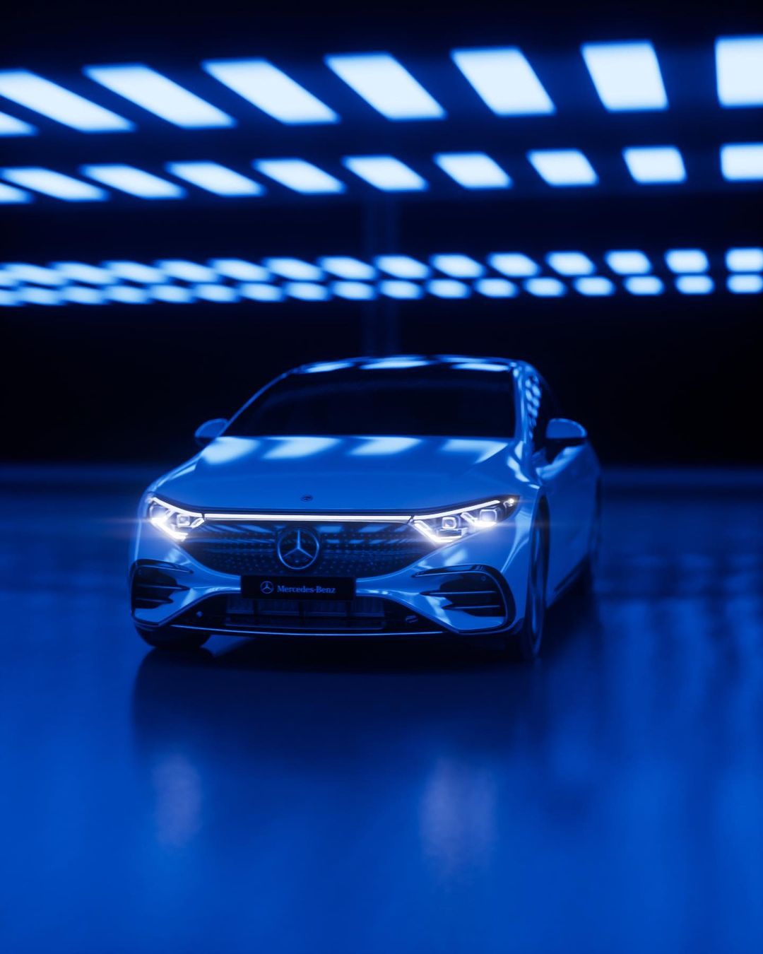 Sleek white Mercedes-Benz EQS car with glowing lights in a futuristic tunnel with repeating rectangular lights in blue hues.