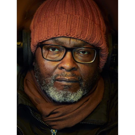 Portrait of a Black man with glasses and a red beanie wearing headphones by Dylan Collard