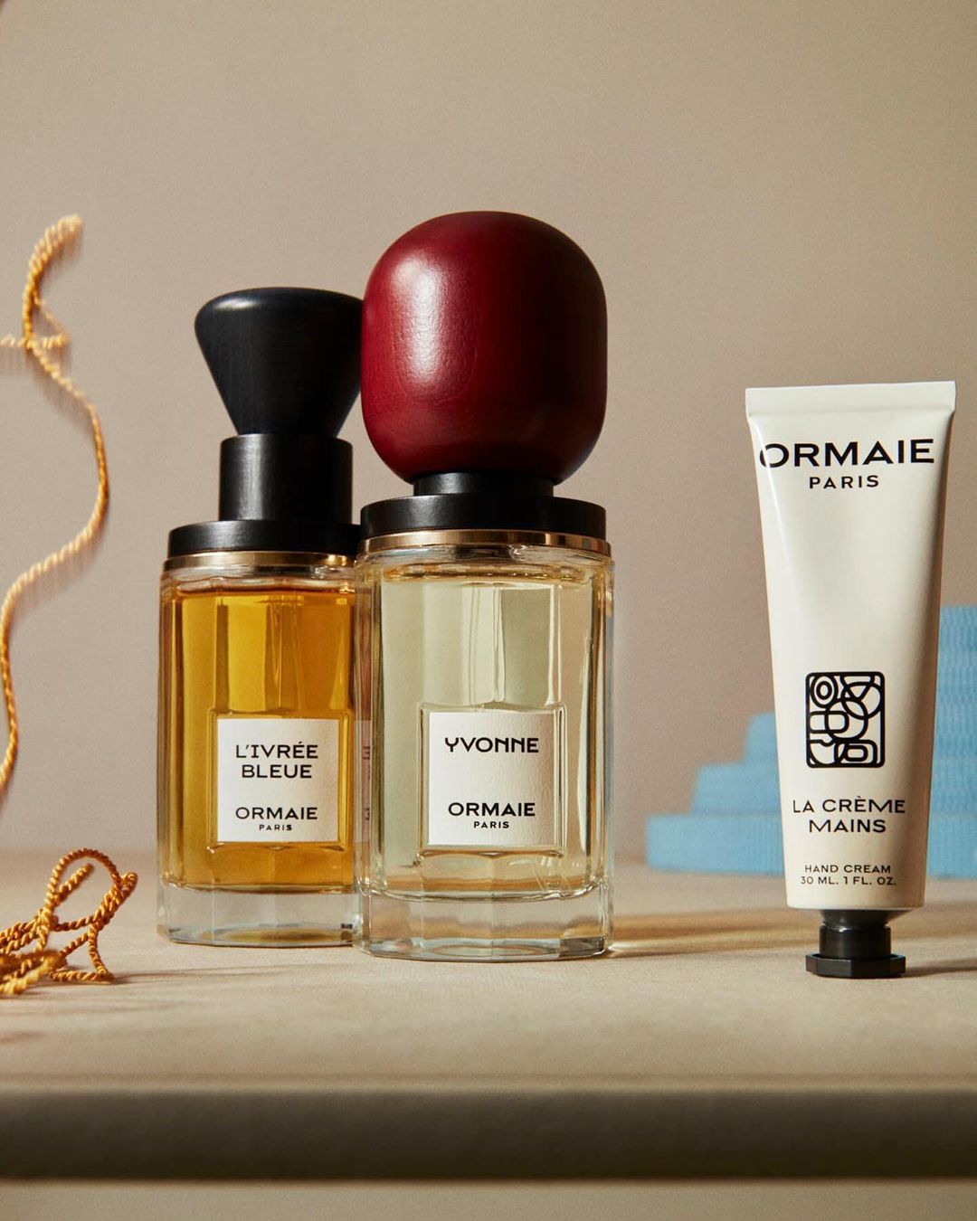 Ormaie Paris perfume bottles and hand cream arranged in a visually appealing still life composition on a neutral surface.