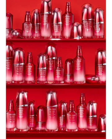 An array of red and white SHISEIDO ULTIMUNE skincare product bottles displayed on three shelves in a brightly lit studio environment.