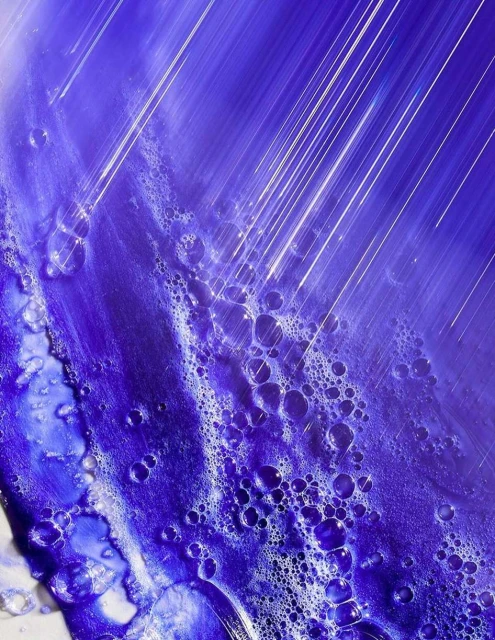 Abstract close-up of purple and white liquid with bubbles and clear plastic wrap, highlighting texture and color for visual interest.