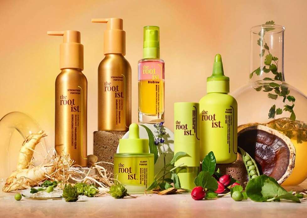 Hair care product line on display in a studio with natural elements like ginseng, herbs, and a glass flask, showcasing a beauty brand.