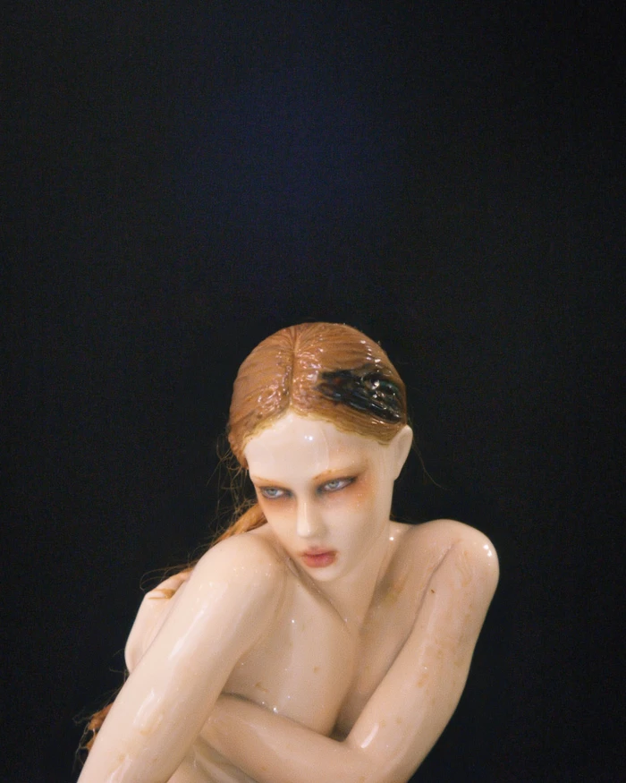 Close-up CGI rendering of a glossy female figure with wet skin and hair against a dark background