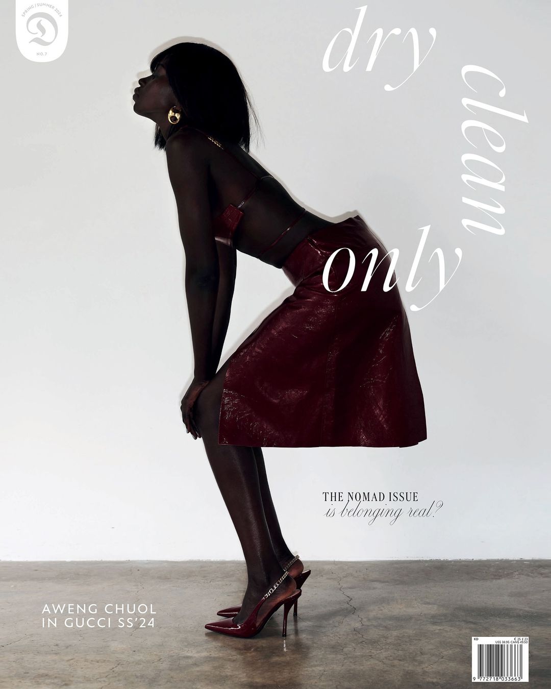 Fashion editorial shot of an African female model in a red skirt and top, kneeling in studio, with a white background and minimal lighting.
