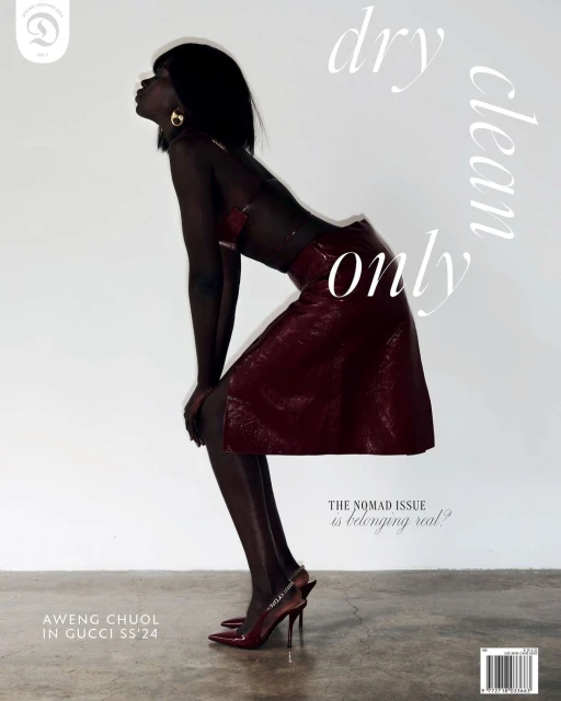 Fashion editorial shot of an African female model in a red skirt and top, kneeling in studio, with a white background and minimal lighting.