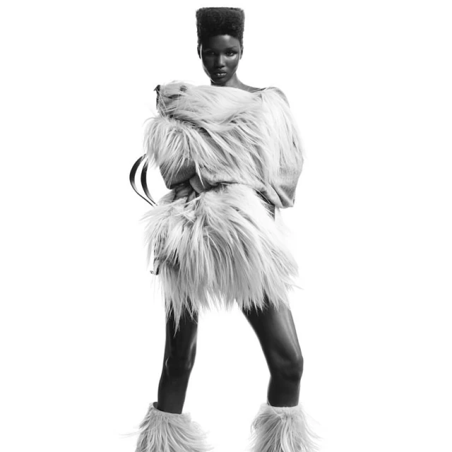 Monochrome studio shot of an African woman wearing a fuzzy outfit, against a white background. Fashion editorial with a soft, textured aesthetic.