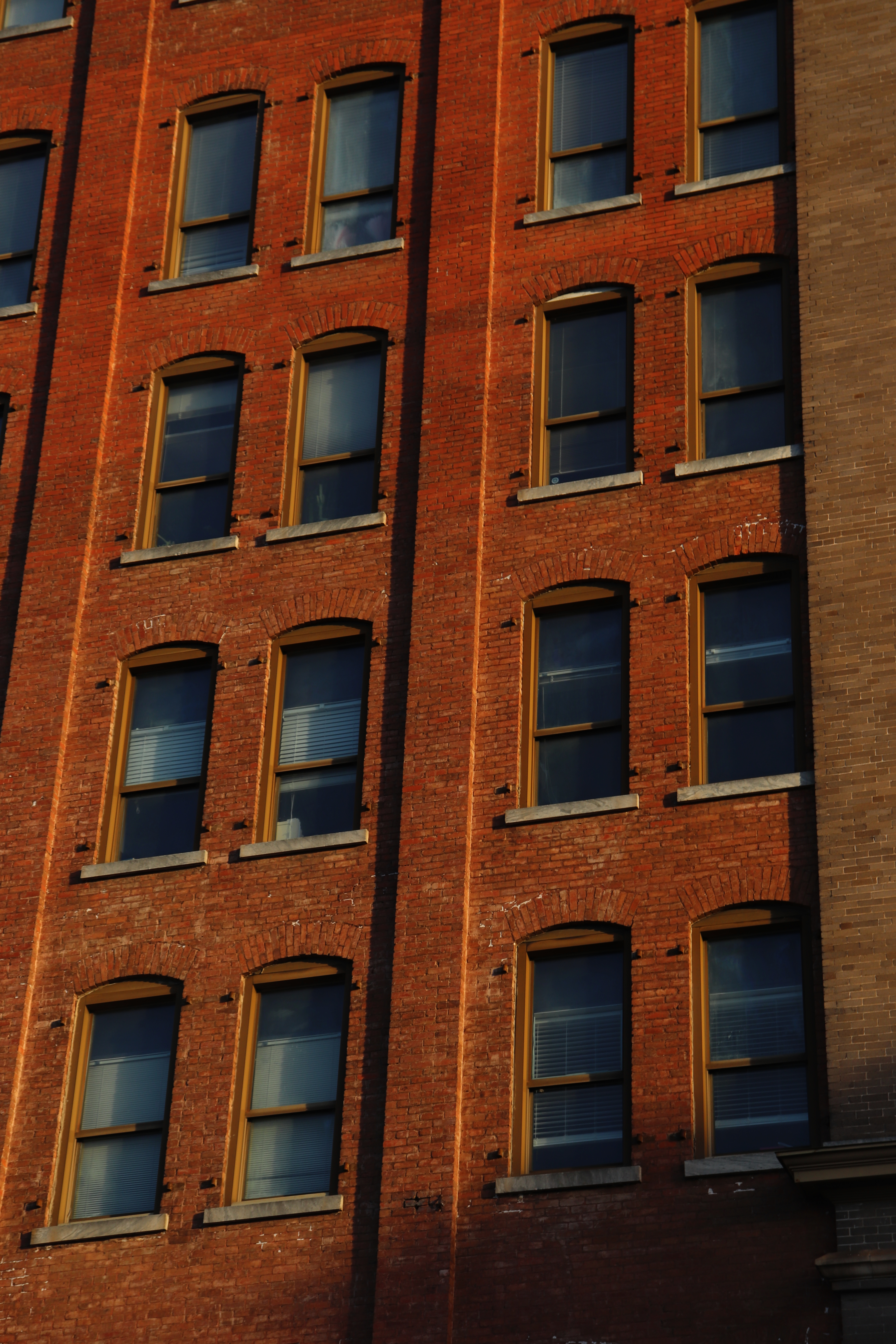 Exterior of a red brick building with symmetrical rows of windows, creating an urban architectural view.