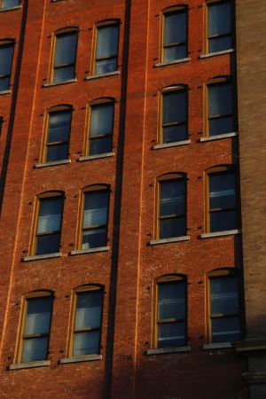 Exterior of a red brick building with symmetrical rows of windows, creating an urban architectural view.