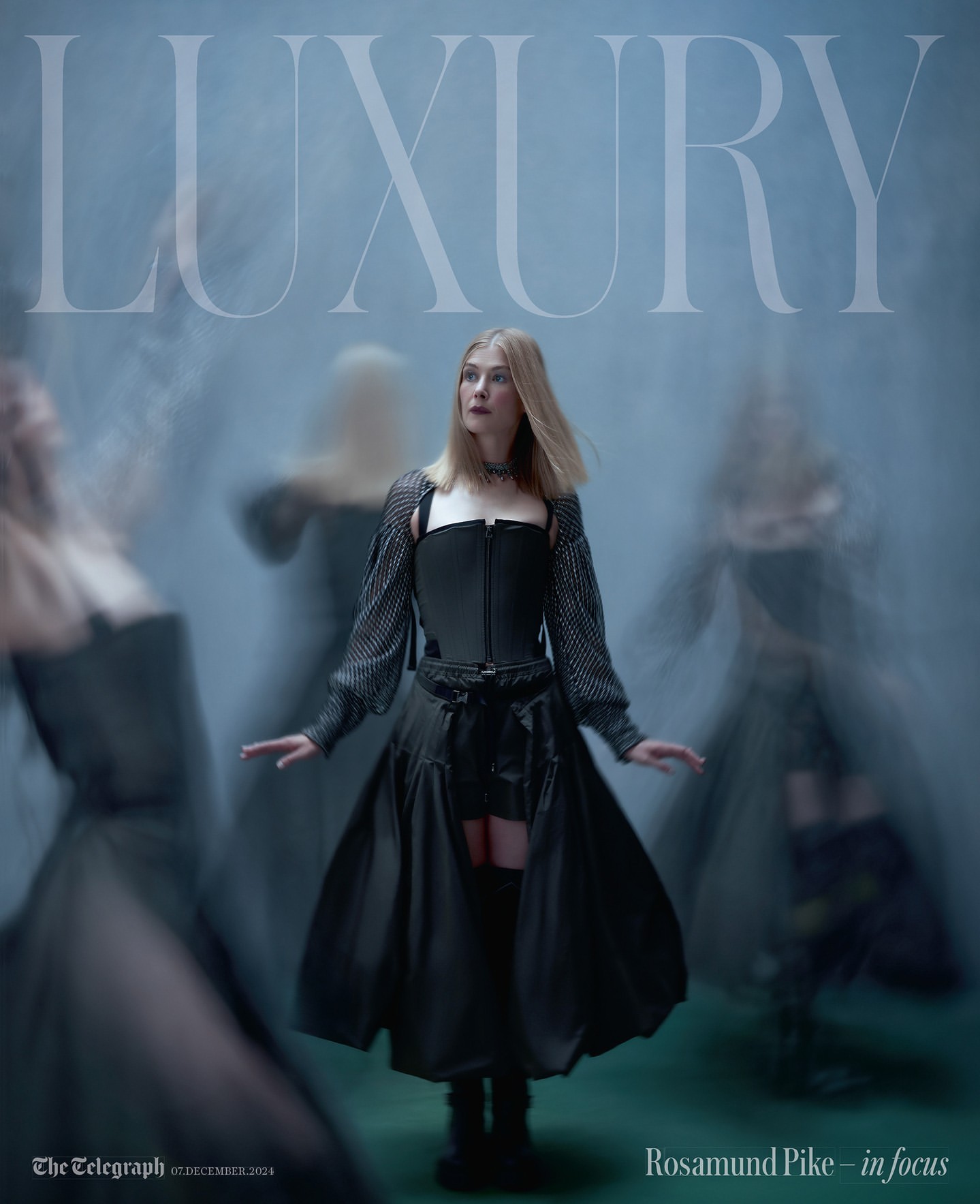 Rosamund Pike in a fashion editorial featuring a woman in a black outfit with layered skirts and sheer sleeves posing in a smoky setting.