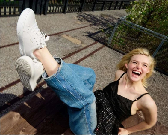 Laughing woman lying outdoors wearing sneakers and jeans. Happy blonde woman posing playfully with white sneakers and blue jeans.
