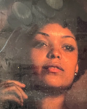Portrait of a woman with dark hair looking upward, indoor with dark background; beauty, hair styling and portrait photography.