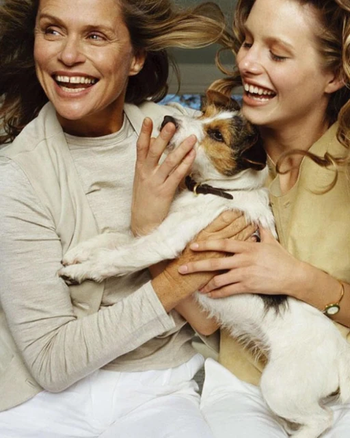 Two adult women smiling with a Jack Russell Terrier dog indoors, wearing casual clothes, sharing a joyful moment, horizontal, natural light.