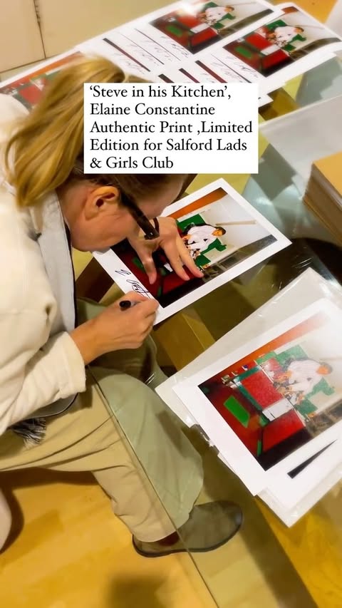 Adult signing authentic print 'Steve in his Kitchen' by Elaine Constantine, a limited edition for Salford Lads & Girls Club.