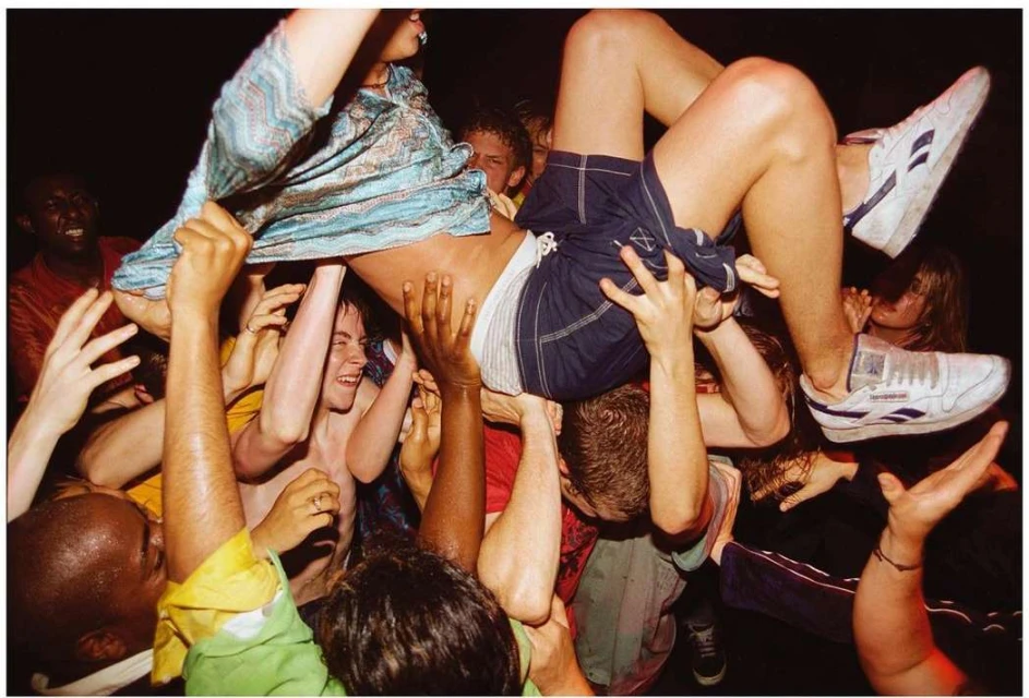 Crowd of people lifting a man in the air at a lively event. Close-up view of a group of people celebrating, with dynamic energy and movement.