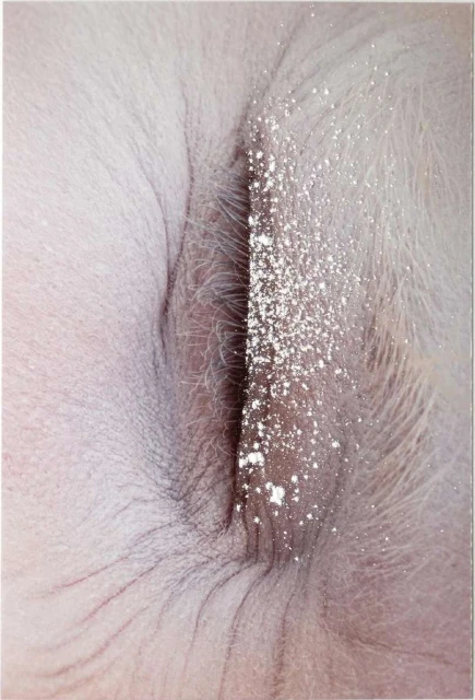 Close-up photograph of a pink and white hairy surface, bisected by a streak of white powder.