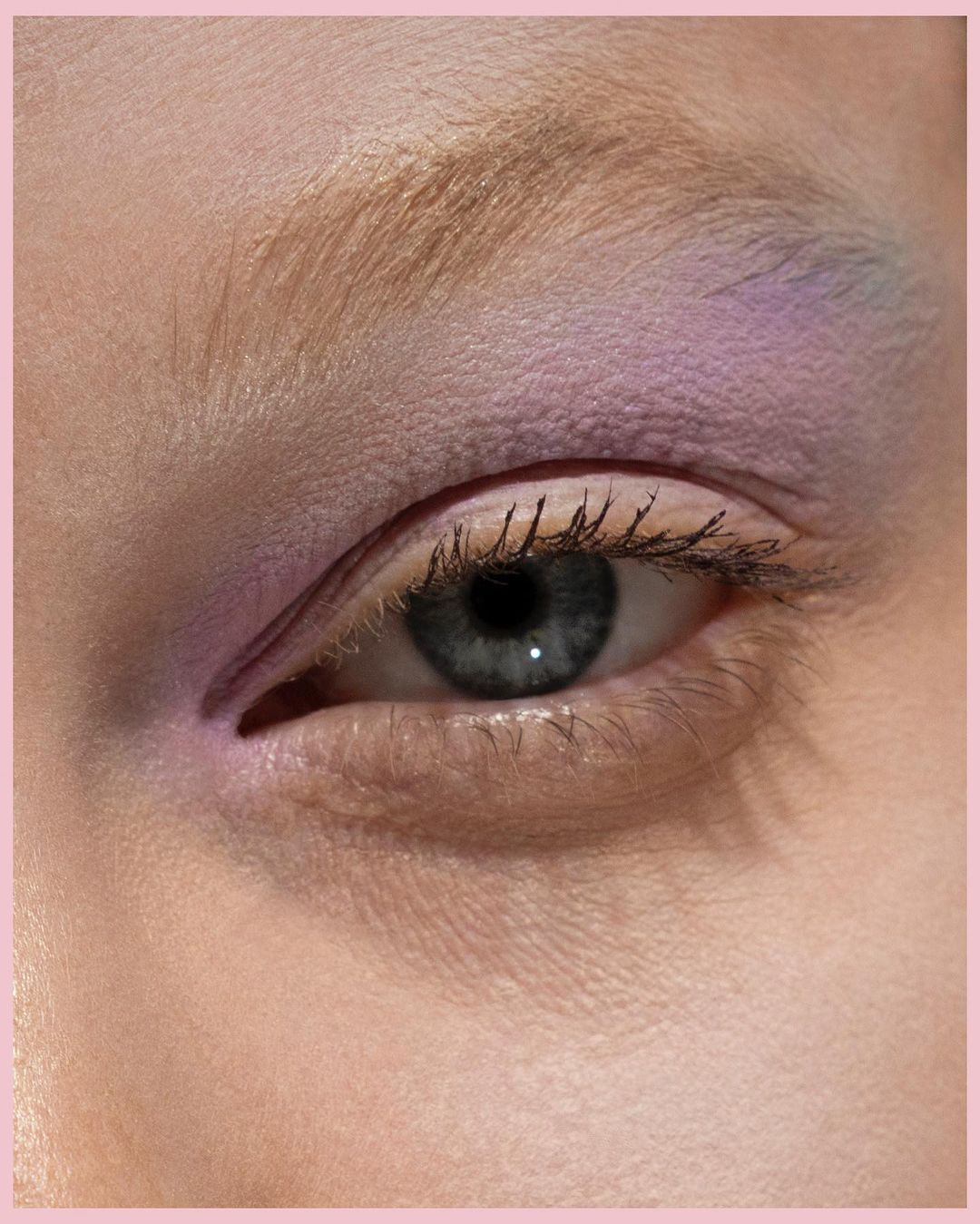 Extreme close-up of a blue eye with soft purple eyeshadow and light eyebrows captured by Eleonore Wismes