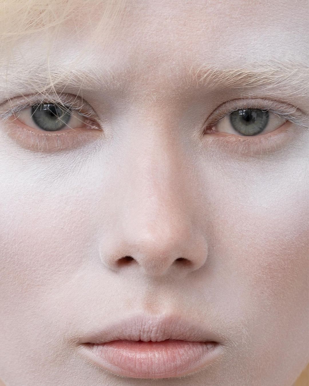 Close-up portrait of a fair-skinned person with blond hair and light eyes, showing the detail of the face and skin texture.