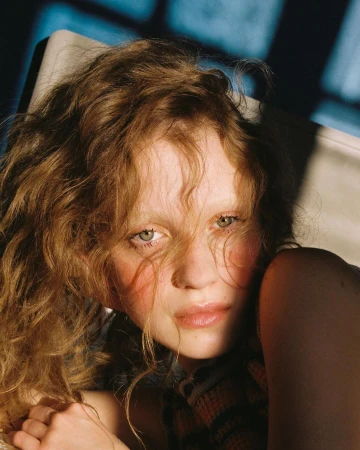 Close-up portrait of a young woman with curly blonde hair and soft lighting by photographer Eleonore Wismes in Paris