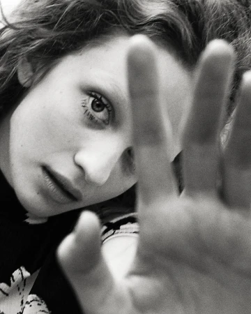 Close-up black and white portrait of a woman with her hand raised in the foreground, shot in Paris by Eleonore Wismes.