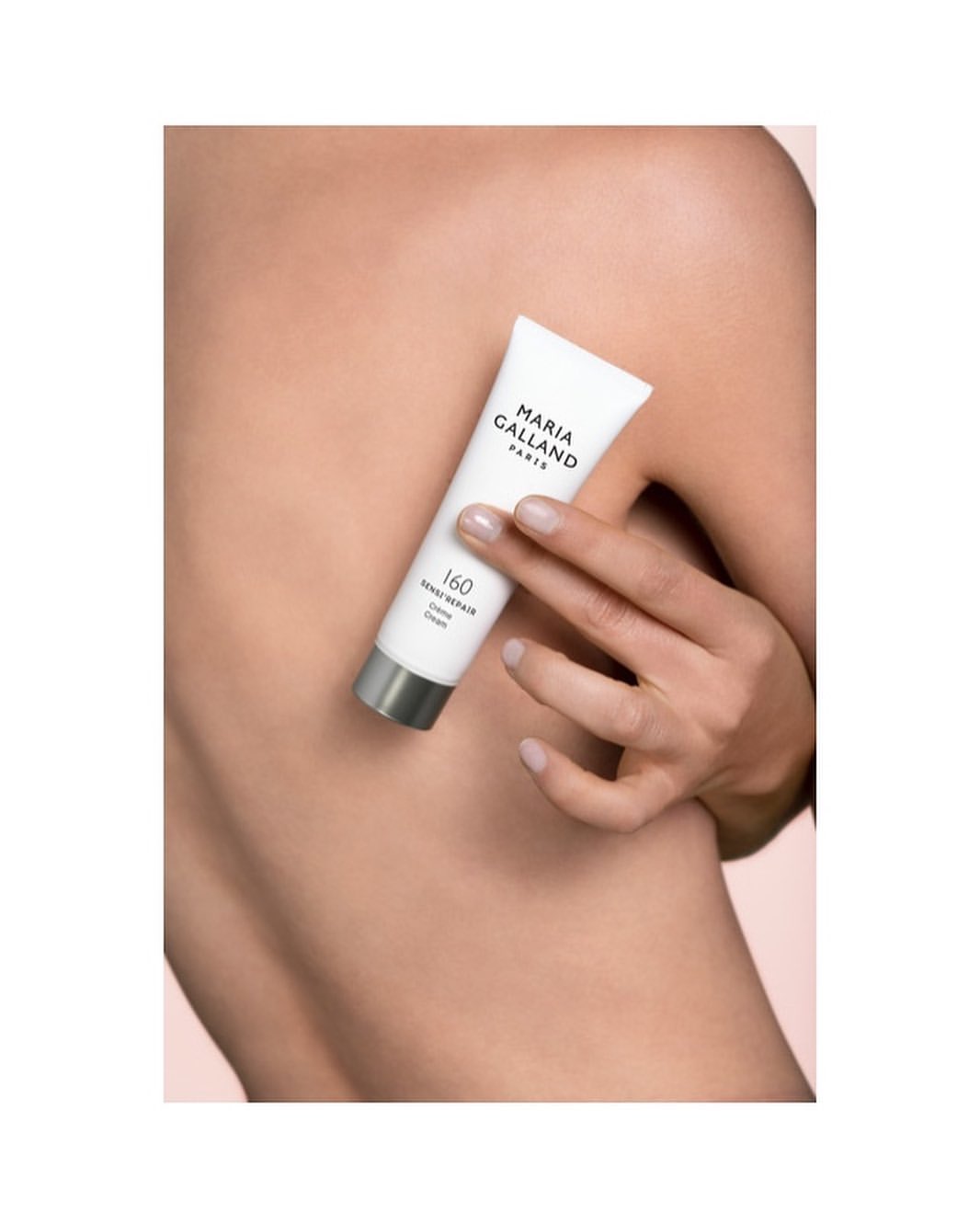 Woman's back with hand holding Maria Galland Paris skincare cream tube; close-up product shot for beauty and skincare advertising.