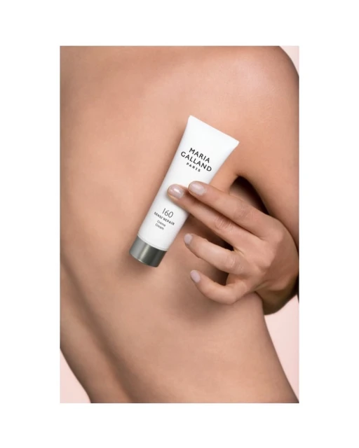 Woman's back with hand holding Maria Galland Paris skincare cream tube; close-up product shot for beauty and skincare advertising.