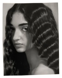 Close-up portrait of a woman with long dark wavy hair and serious expression by Eleonore Wismes in Paris