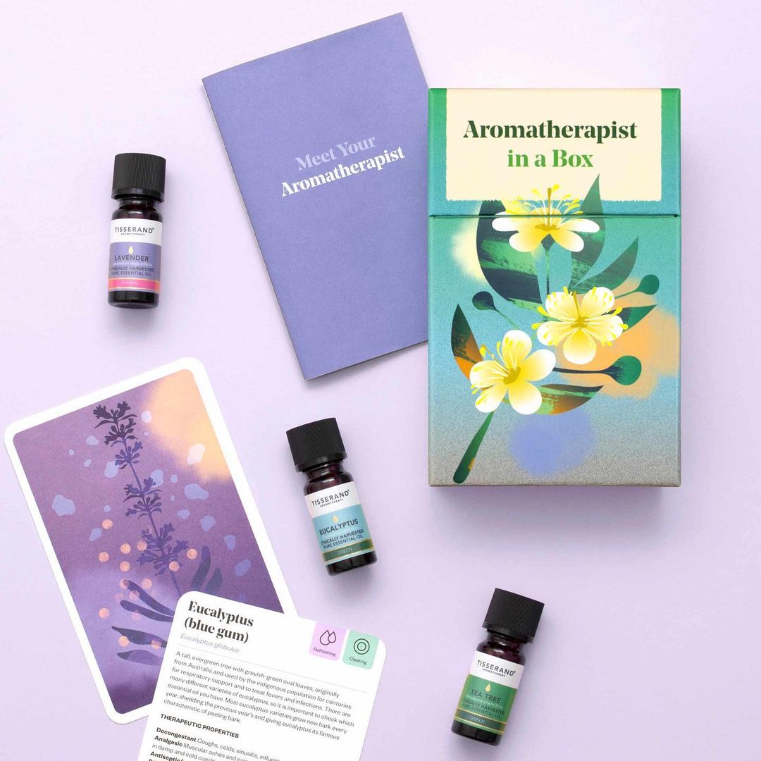 Aromatherapy kit featuring essential oil bottles, information cards, and a decorative box, set on a lavender background. Wellness concept.