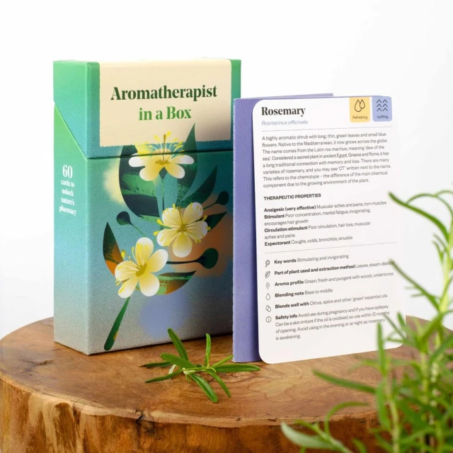 Aromatherapy product box and information card on a wooden surface with rosemary leaves, presenting natural wellness solutions.