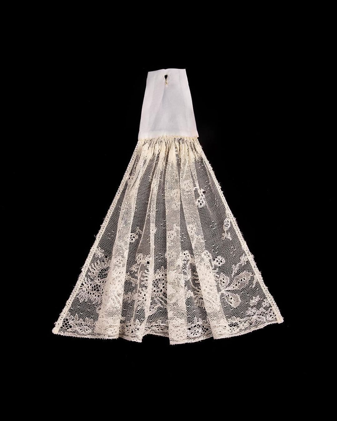 Lace decorative item against black background showcasing intricate floral and geometric patterns in off-white hue, creating a delicate aesthetic.