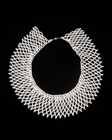 Elegant white beaded necklace in a net-like design against a stark black background, showcasing intricate craftsmanship and texture.