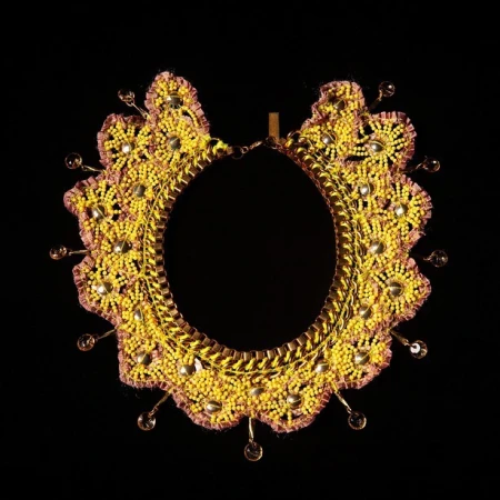 Artisan-crafted beaded collar necklace, featuring yellow beads, gold trim, and amber glass bead accents, against a stark black backdrop.