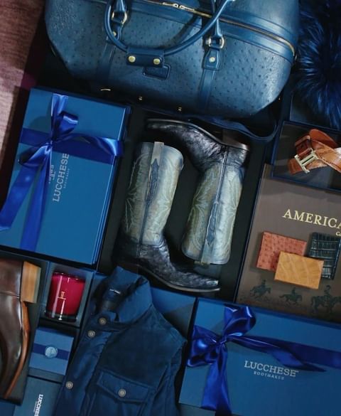 A curated collection of fashion items including leather boots, a duffel bag, a vest, and gift boxes arranged in an orderly manner.