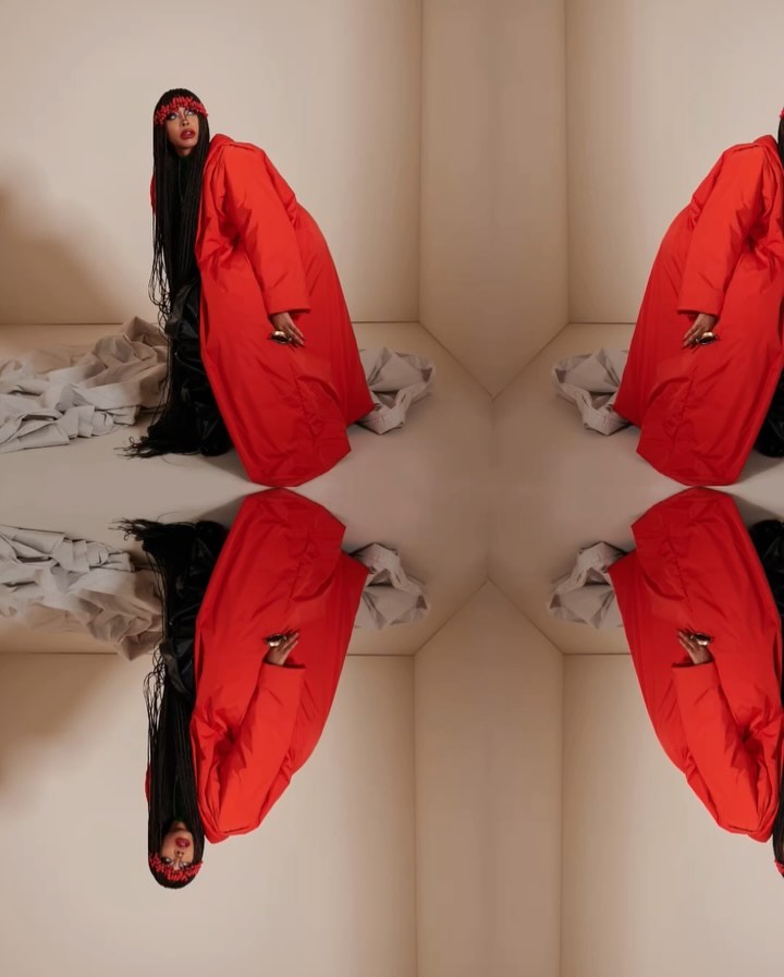 Woman wearing a red coat and headscarf in a kaleidoscopic mirrored pattern, creating a symmetrical, abstract fashion photograph.