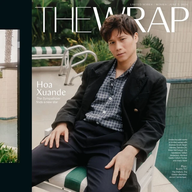 Hoa Xuande, star of 'The Sympathizer', poses on a magazine cover in a patterned shirt and blazer, seated outdoors by a pool.