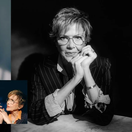 Black and white portrait of a mature adult woman with short hair wearing glasses and a striped blazer, with hands clasped.