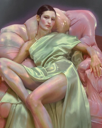 A woman in a pale green satin dress is seated on a pink, inflated-looking chair. The portrait-style shot features a soft lighting mood.