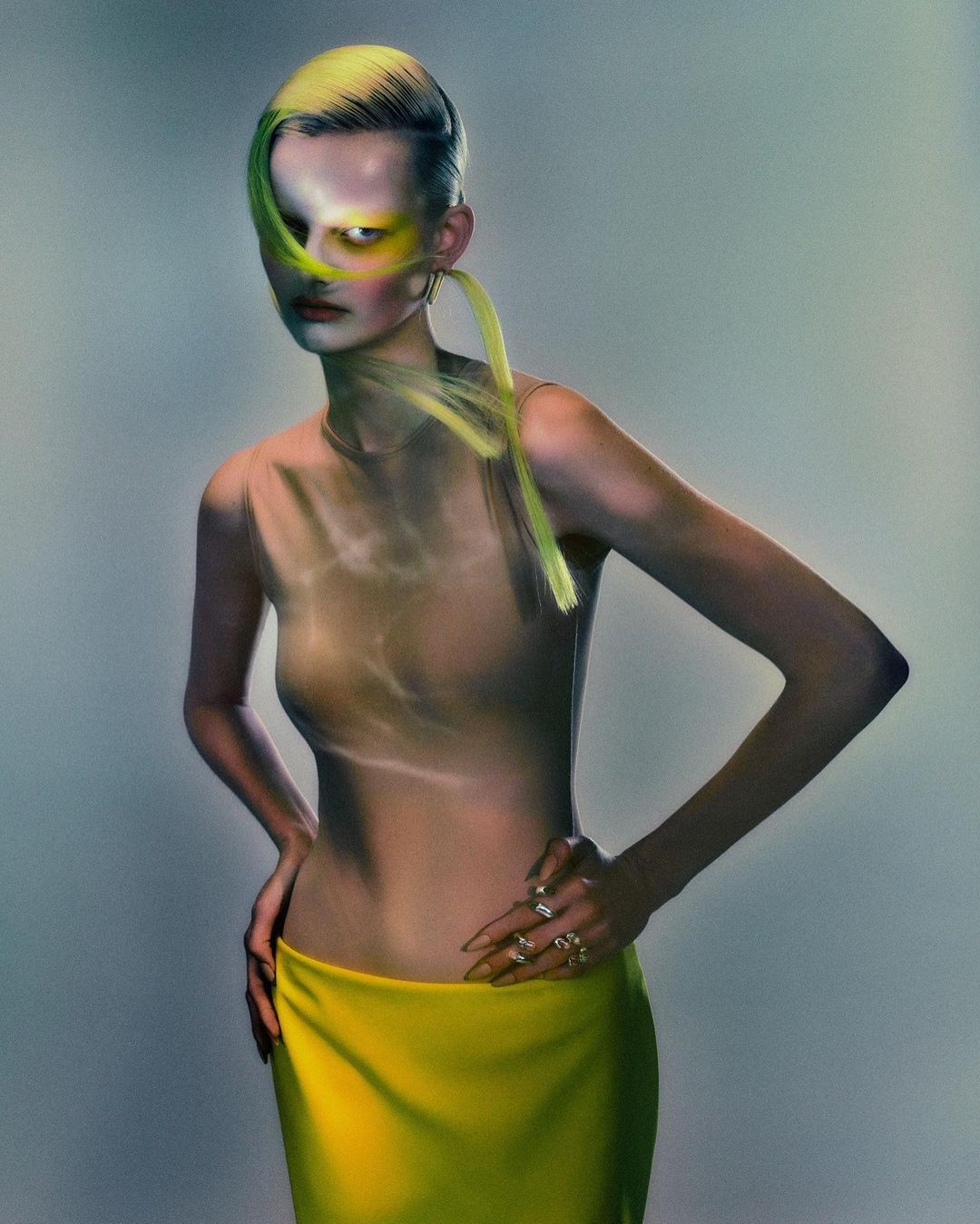 Fashion portrait of a woman with pale skin, yellow hair and yellow skirt in front of a neutral background in a photo studio.