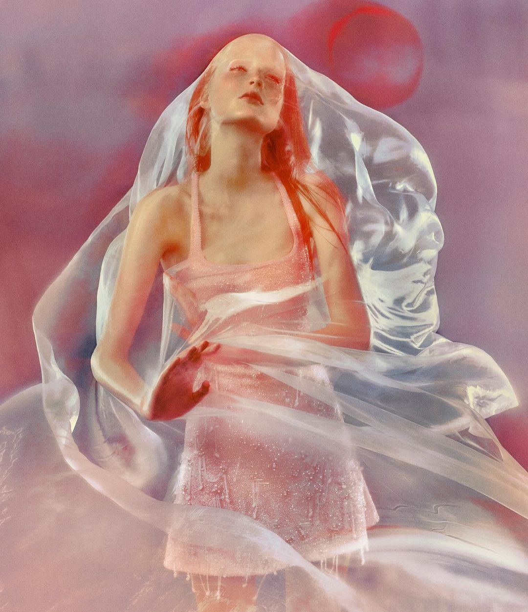 Artistic portrait of a fair-skinned woman wearing a pink dress and veil in a soft-focus, pastel-toned background with a dreamy quality.