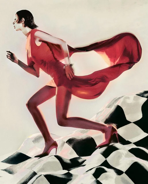 Elegant woman in motion wearing a red dress and heels, a flowing cape, set against a black and white checkered surface.