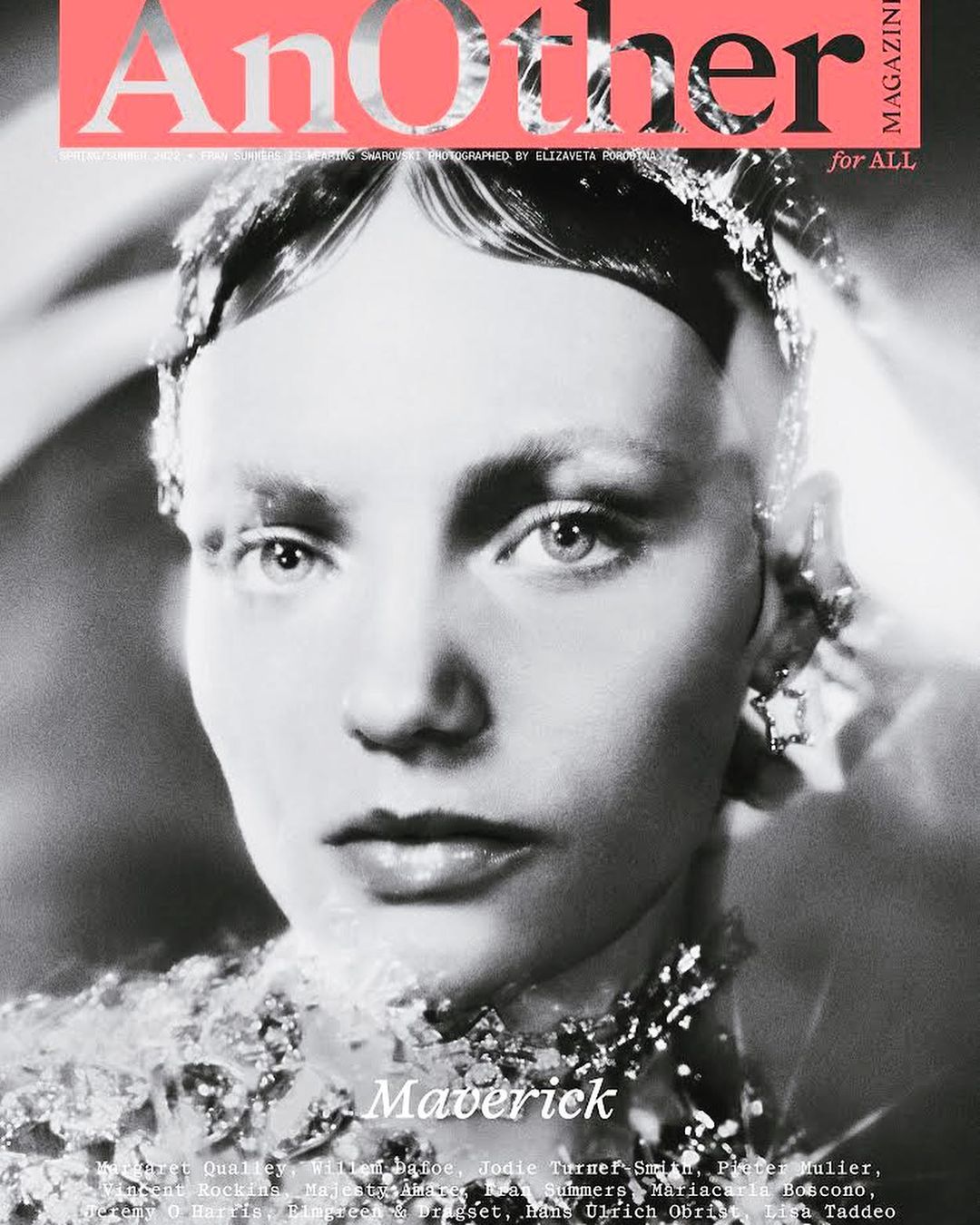 Monochrome close-up of a person with ornamented jewelry and heavy makeup, featured on the cover of Another Magazine.