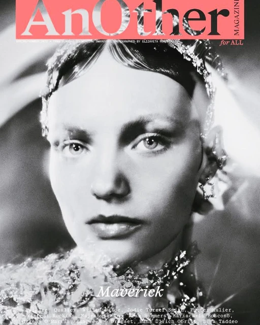 Monochrome close-up of a person with ornamented jewelry and heavy makeup, featured on the cover of Another Magazine.