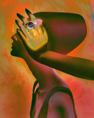 Profile of a woman with a hand raised to her face wearing a prominent ring, photographed by Elizaveta Porodina in warm tones.
