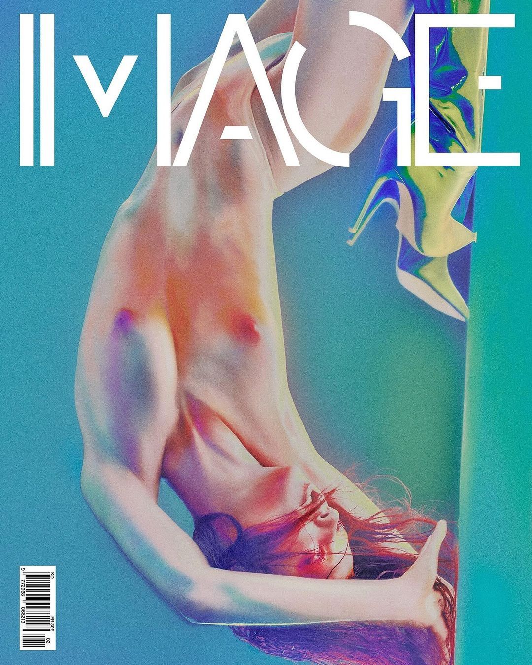 Upside-down studio portrait of a nude adult female with shiny high-heeled boots against a blue and green gradient backdrop.