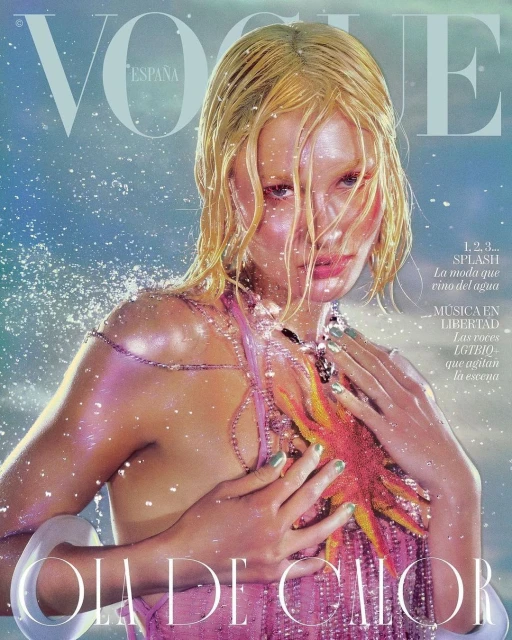 Vogue España cover featuring a blonde woman with wet hair, wearing a pink halter top and jewelry, posing in front of a blue background.