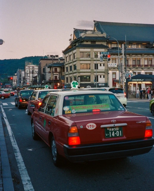 Japanese taxi cabs lined up on a city street with traditional architecture and soft sunset light, creating a travel destination scene.