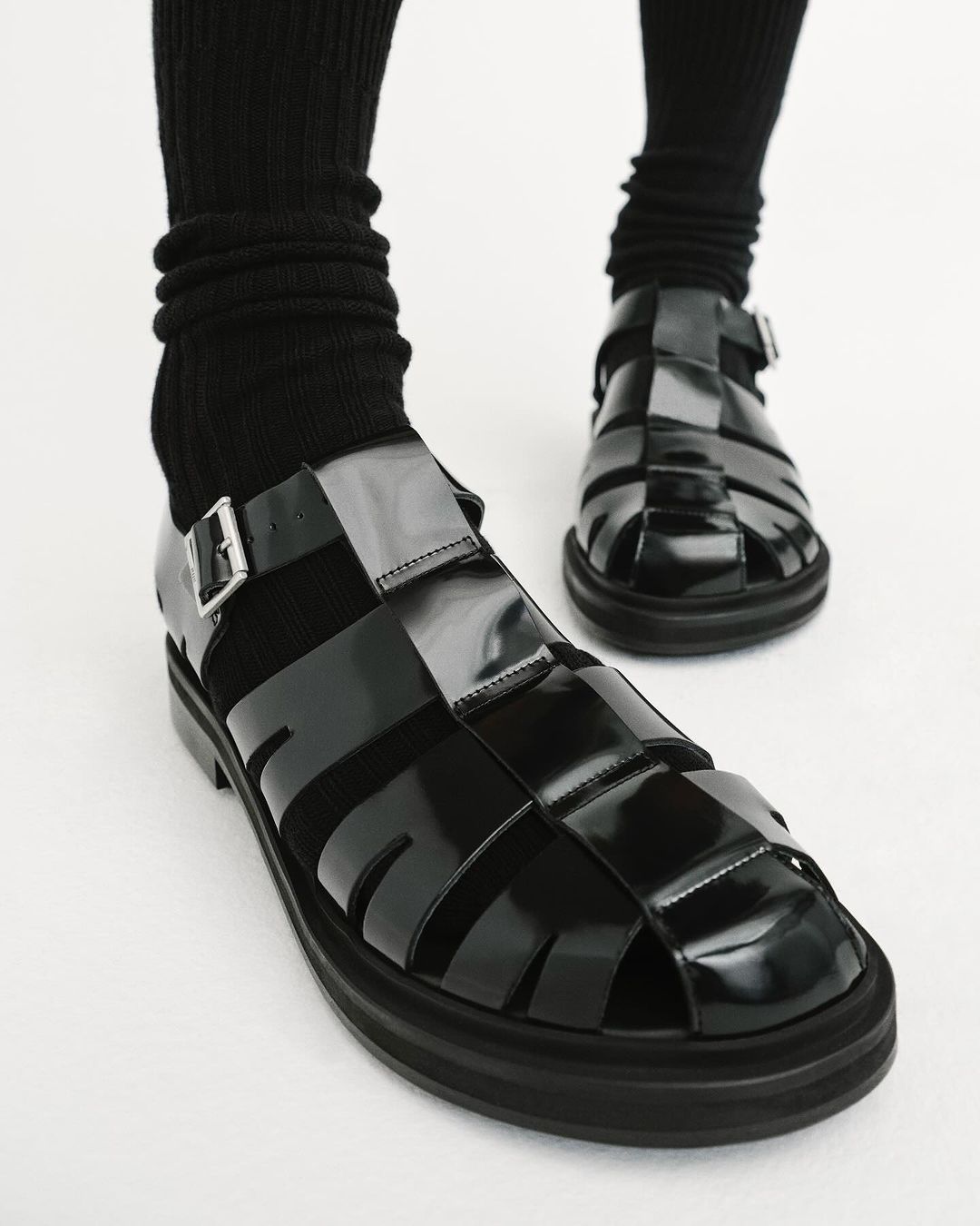 Close-up studio shot of black fisherman sandals with buckles and black socks on a white background. Stylish footwear for fashion.