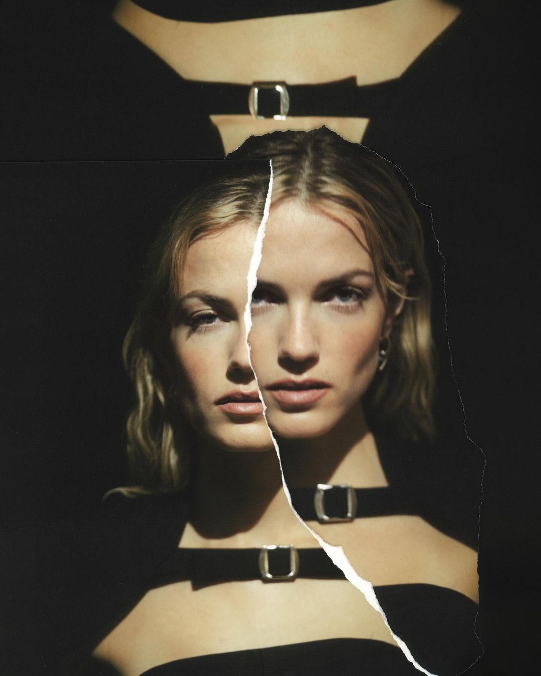 Portrait of a woman with blonde hair wearing a black top with metal buckles, against a dark background, with torn paper effect.