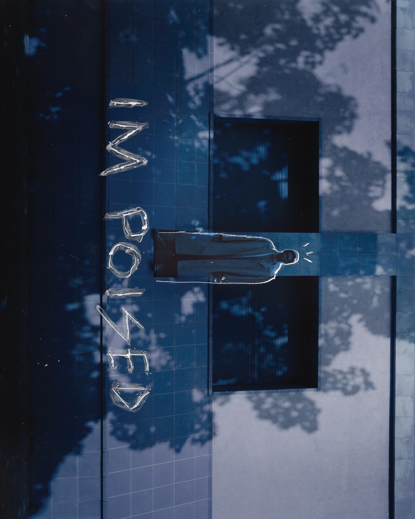 Abstract blue-toned shot featuring a person's silhouette on a geometric grid, architectural details, tree shadows, and bold text.